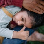 Sad little multiracial girl in mother arms, worrying. Domestic violence concept.
